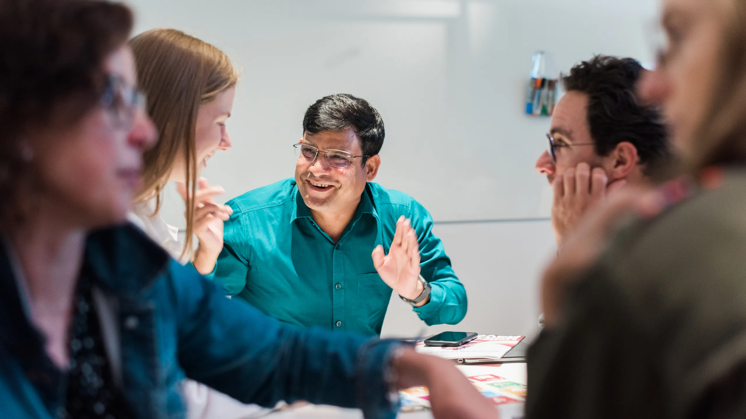 A participant laughing mid-conversation across a seminar table at a UCL EdTech Labs workshop